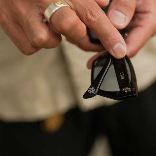 Artist Kentaro Yoshida holding black mineral glass sunglasses 